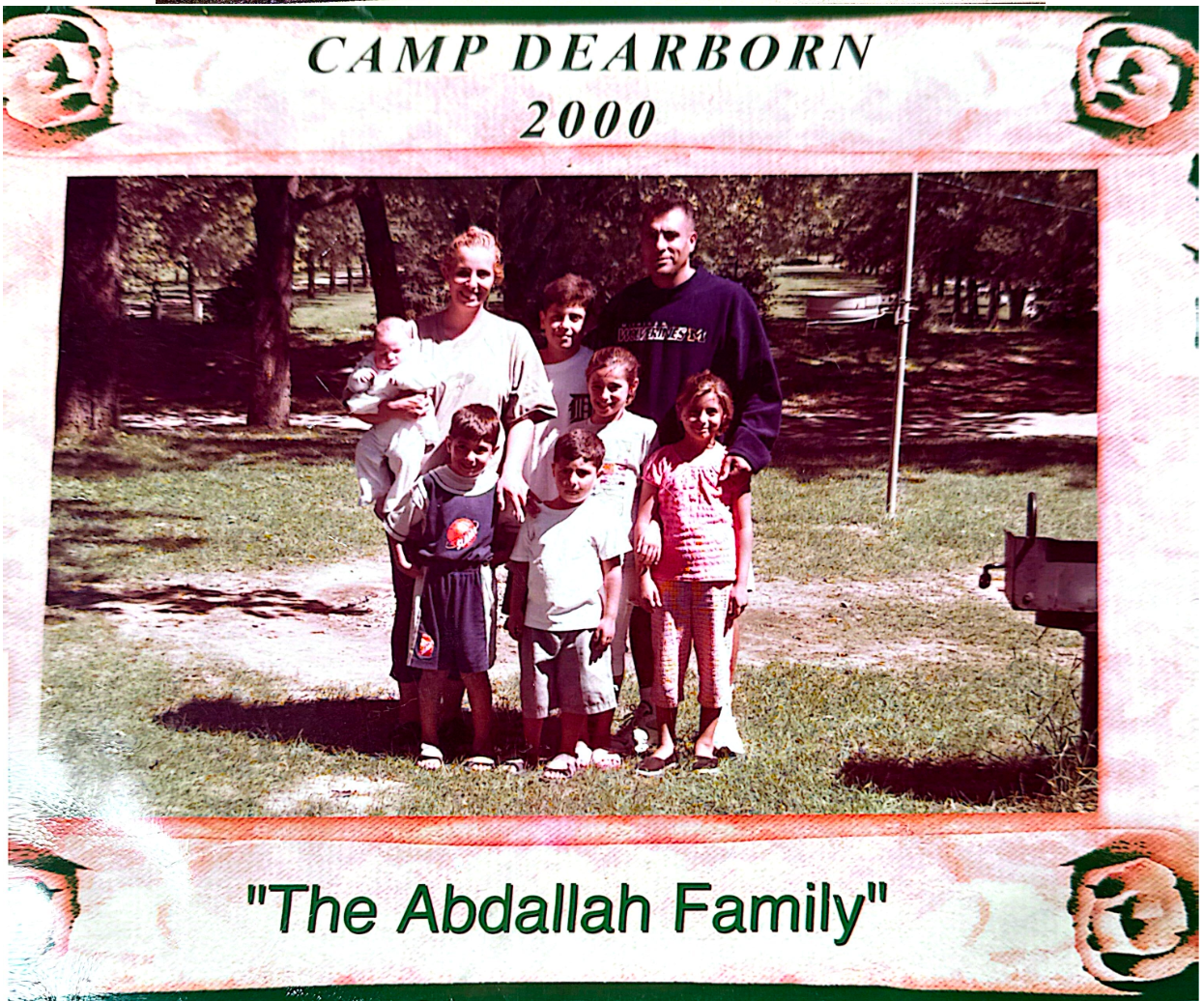 Family photo at Camp Dearborn in 2000. Group poses outdoors: adults, children. Green grass, trees in background.