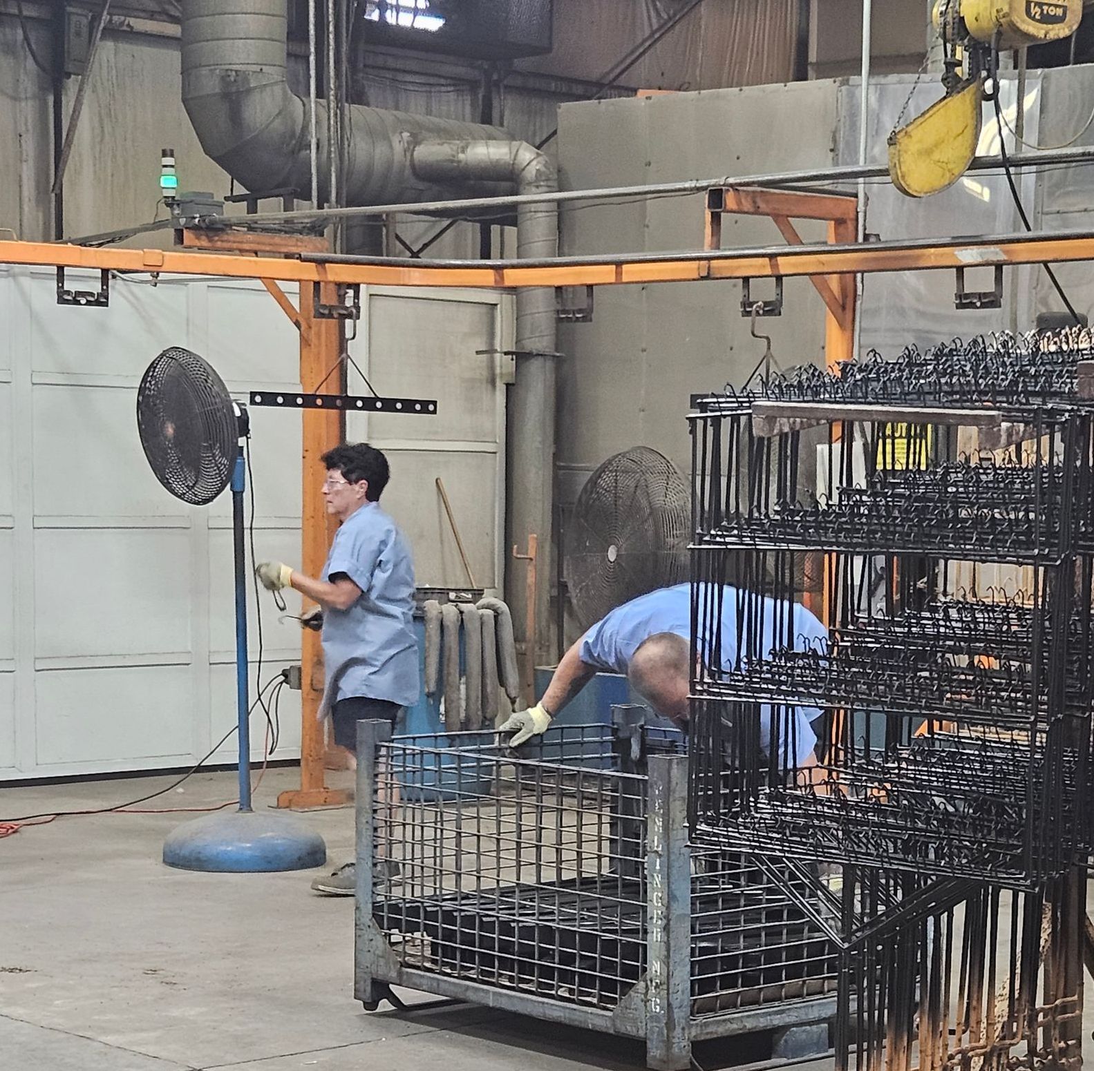 People working in a factory with a fan hanging from the ceiling