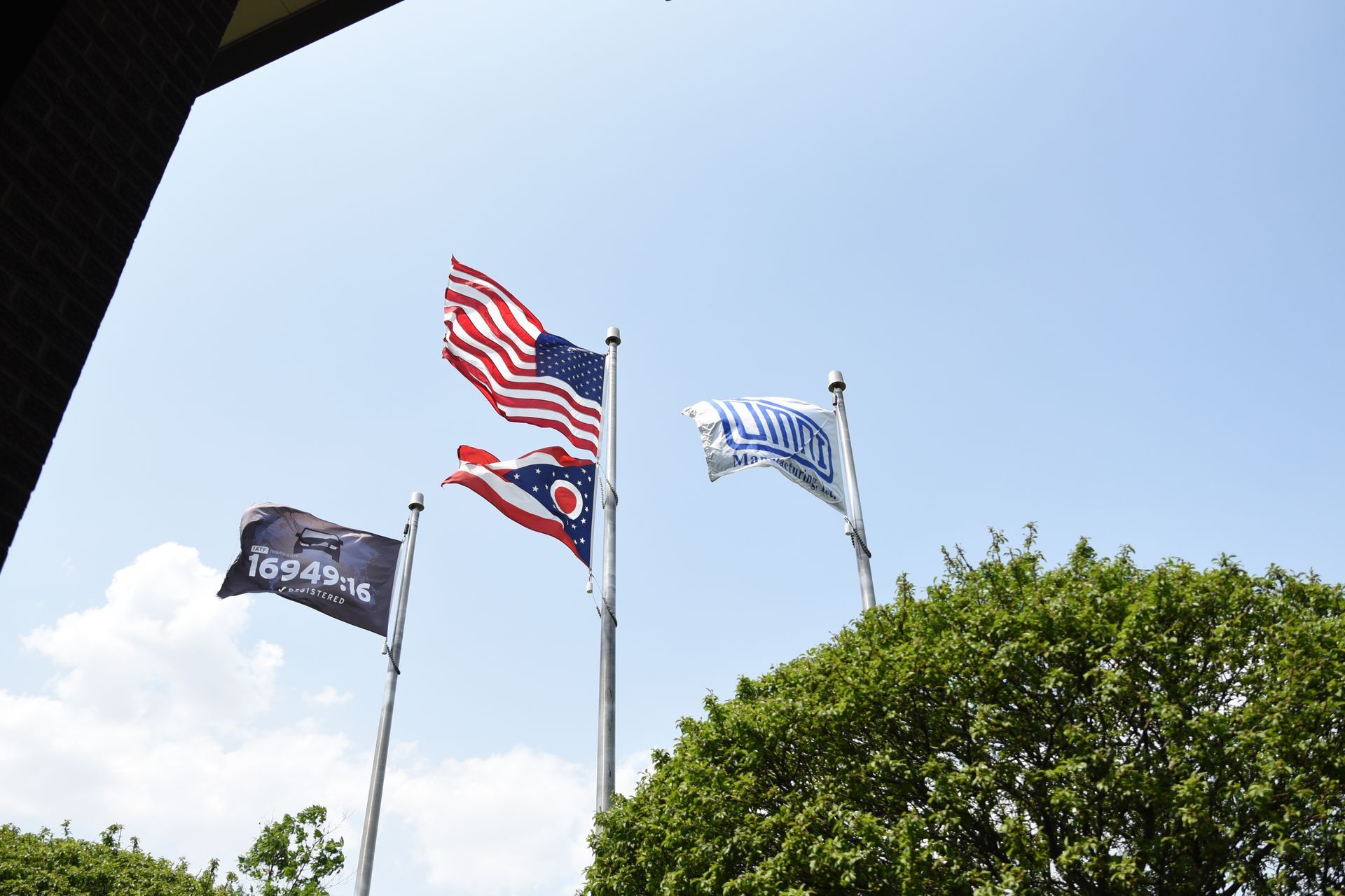 Three flags are flying in the wind on a pole.