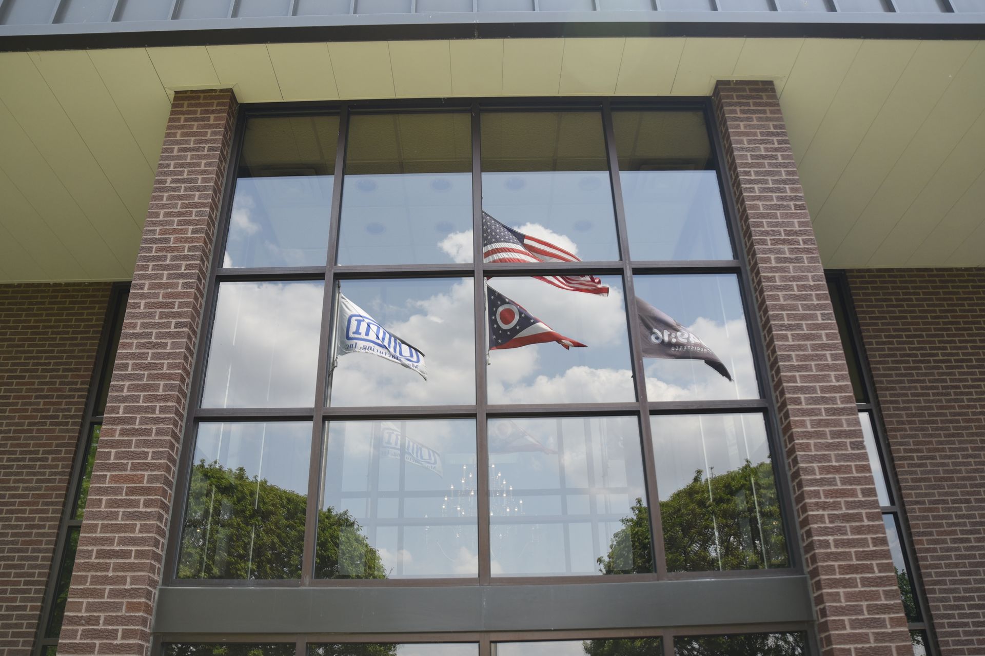 The flags are reflected in the windows of a brick building.