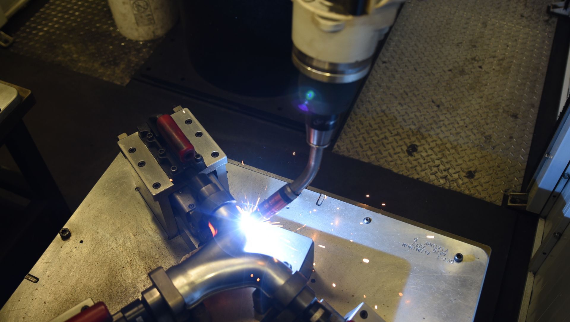 A machine is welding a pipe on a table.