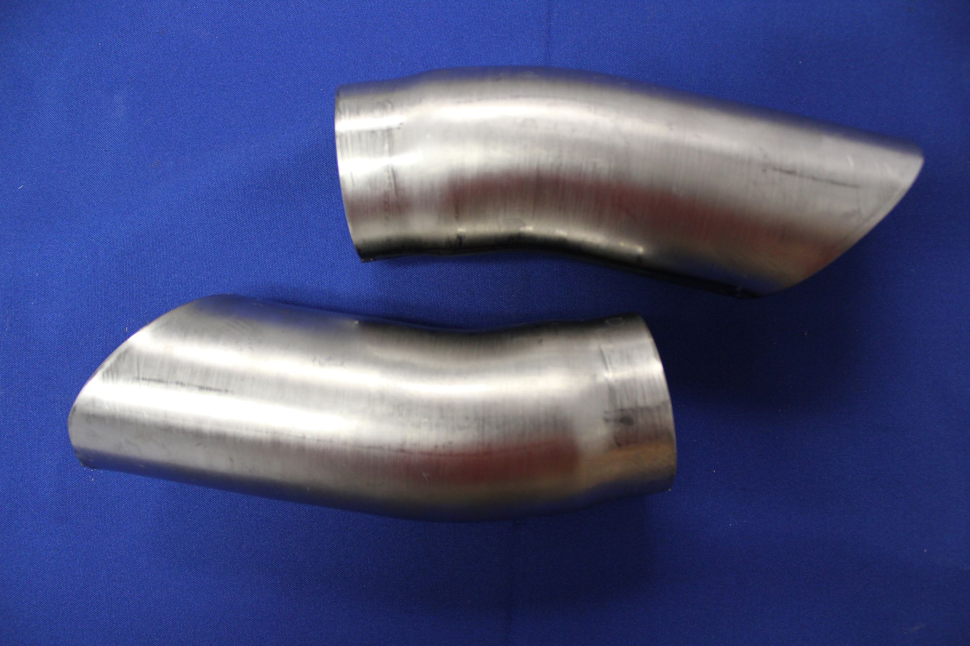 Two stainless steel pipes are sitting on a blue surface.