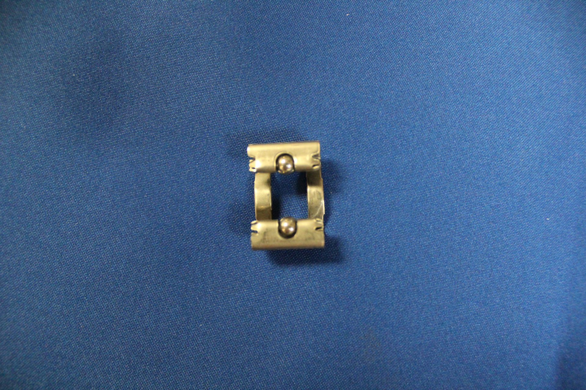 A small gold object is sitting on top of a blue cloth.