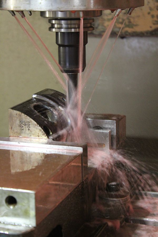 A machine is cutting a piece of metal with liquid coming out of it.