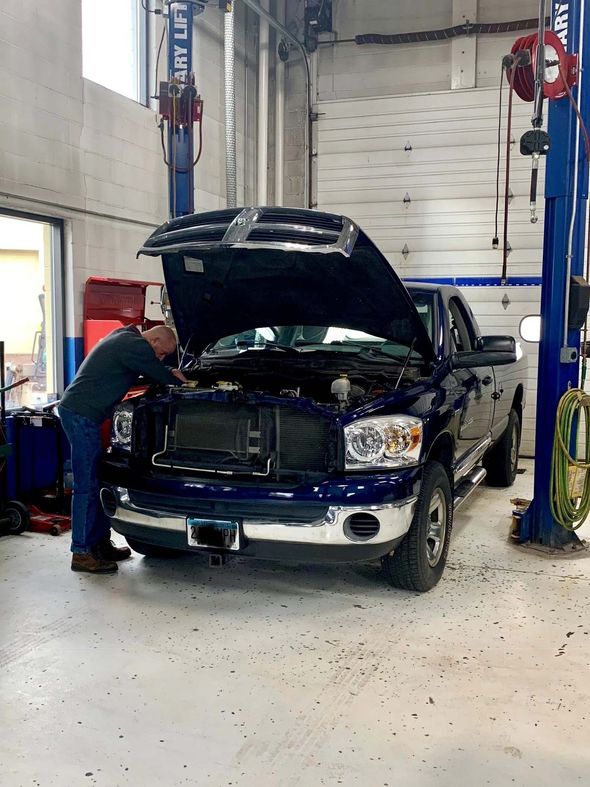 Man repairing a dark blue car — Oak Park Heights, MN — Stillwater Auto Clinic