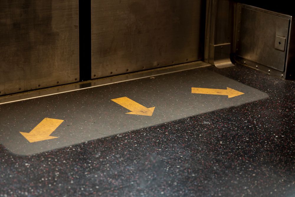 Yellow arrows on a floor mat inside a subway car point towards the right, guiding passengers.