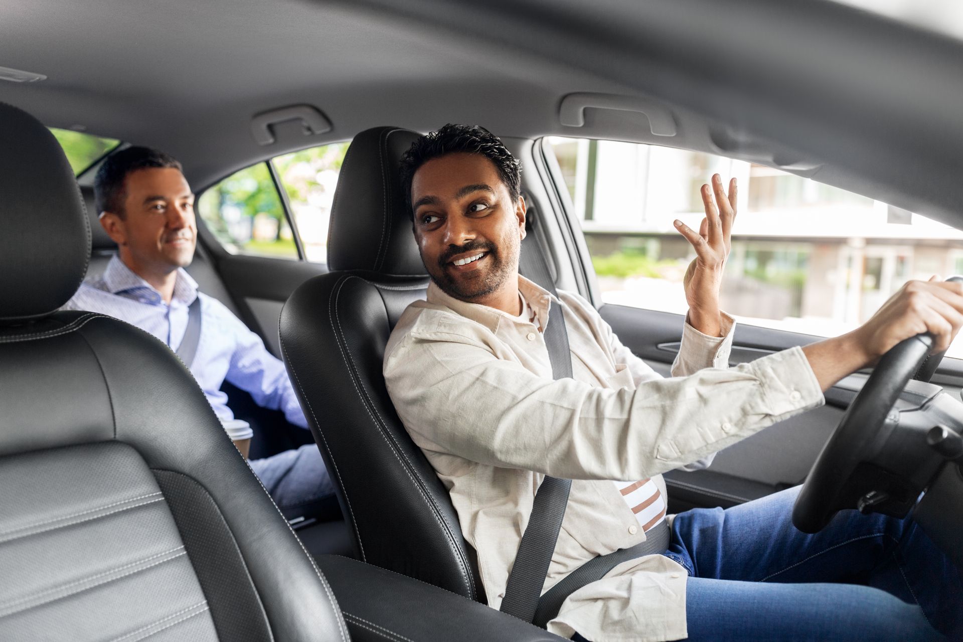 Man driving and gesturing in a car; passenger in the back seat.