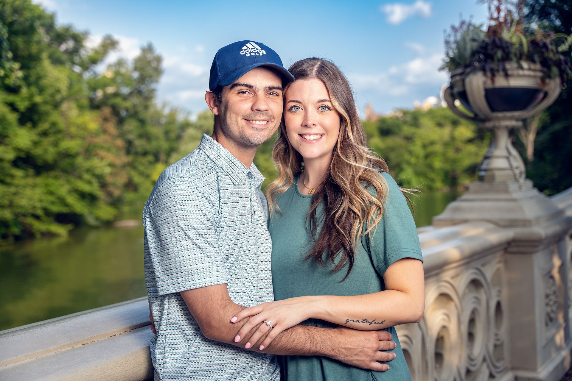 A man and a woman are posing for a picture on a bridge.