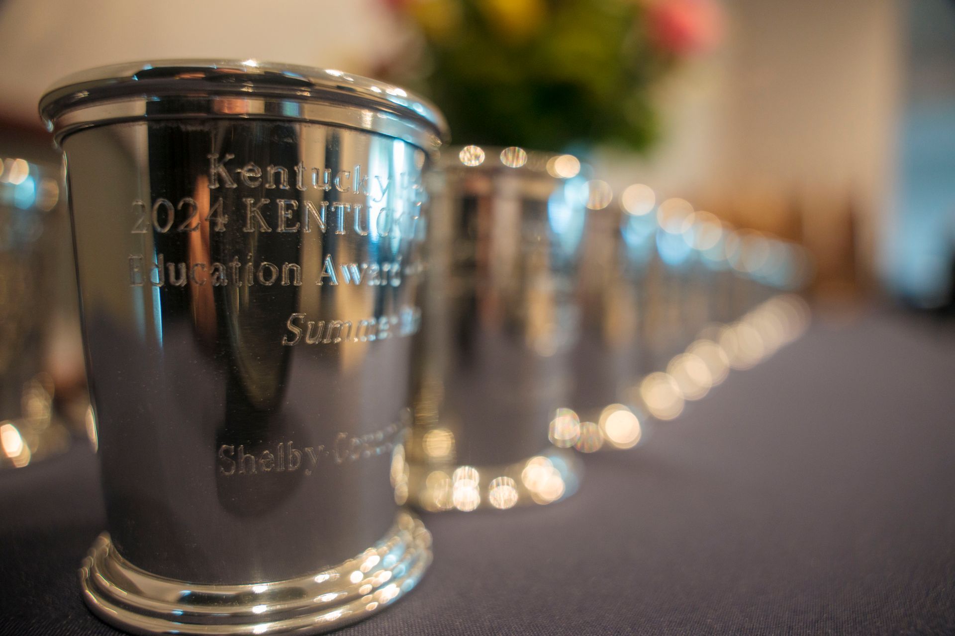 A row of silver trophies are sitting on a table.