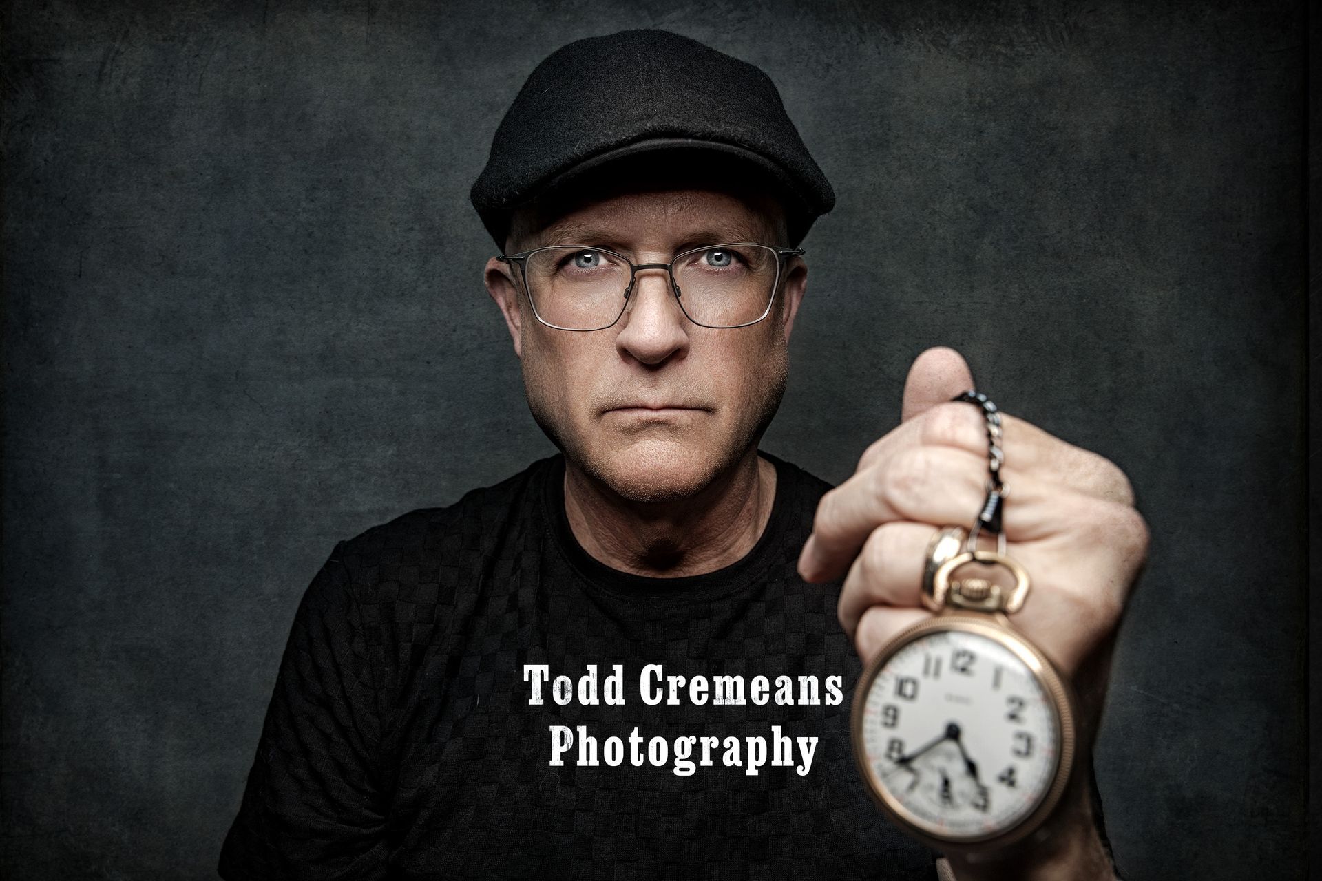 A man wearing glasses and a hat is holding a pocket watch