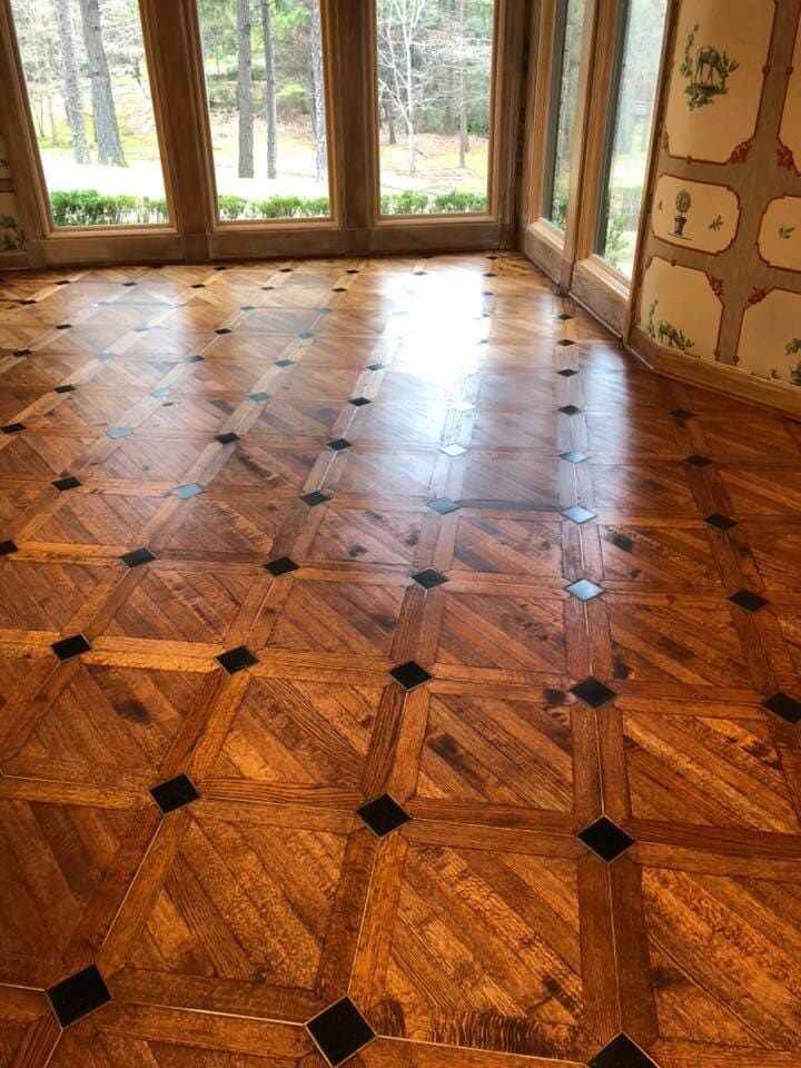 A room with a wooden floor and lots of windows.