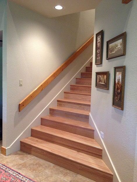 A wooden staircase with a wooden railing and pictures on the wall
