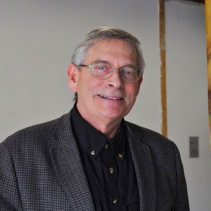 A man wearing glasses and a suit is smiling for the camera