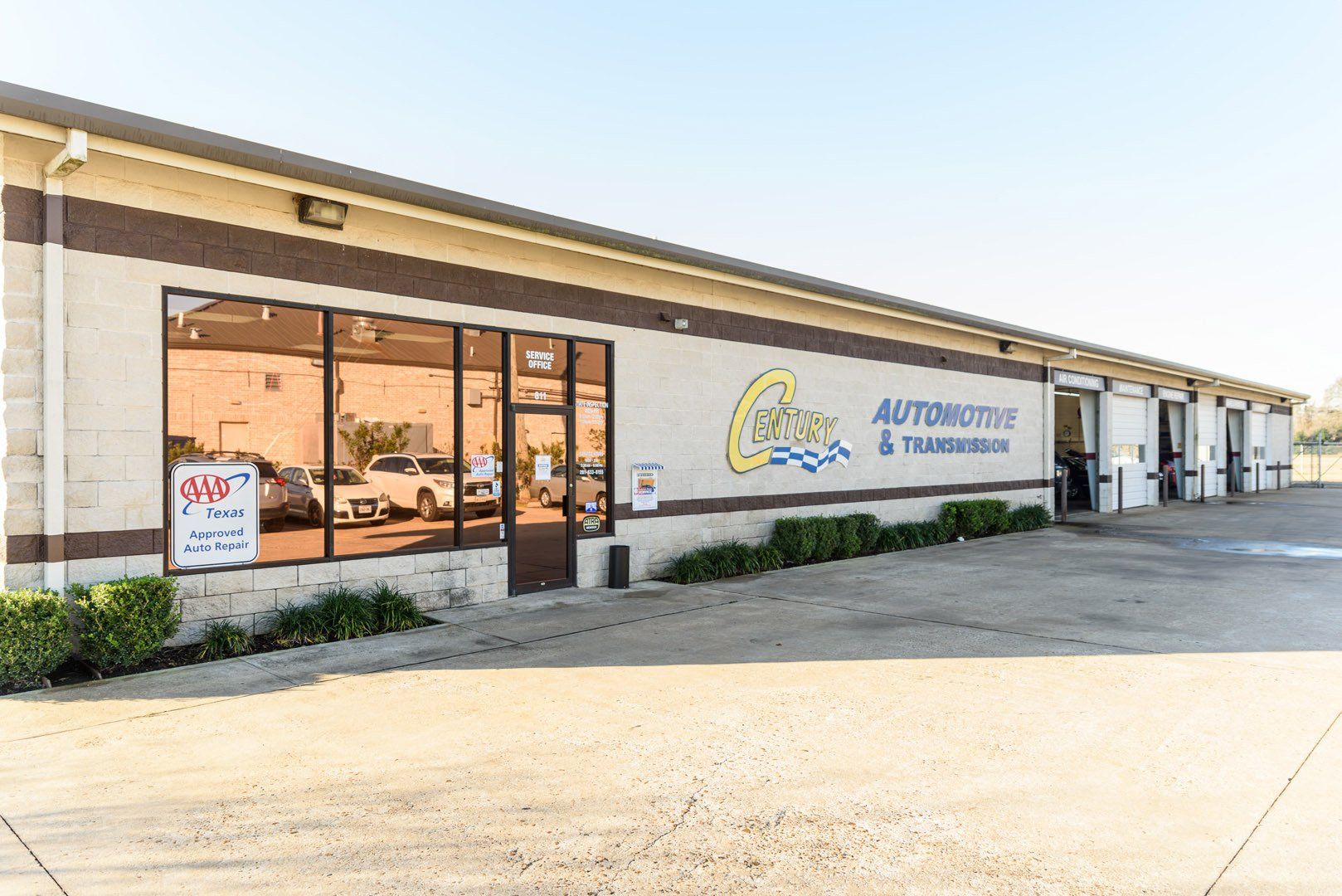 Exterior of auto repair shop with large windows and open garage bays.