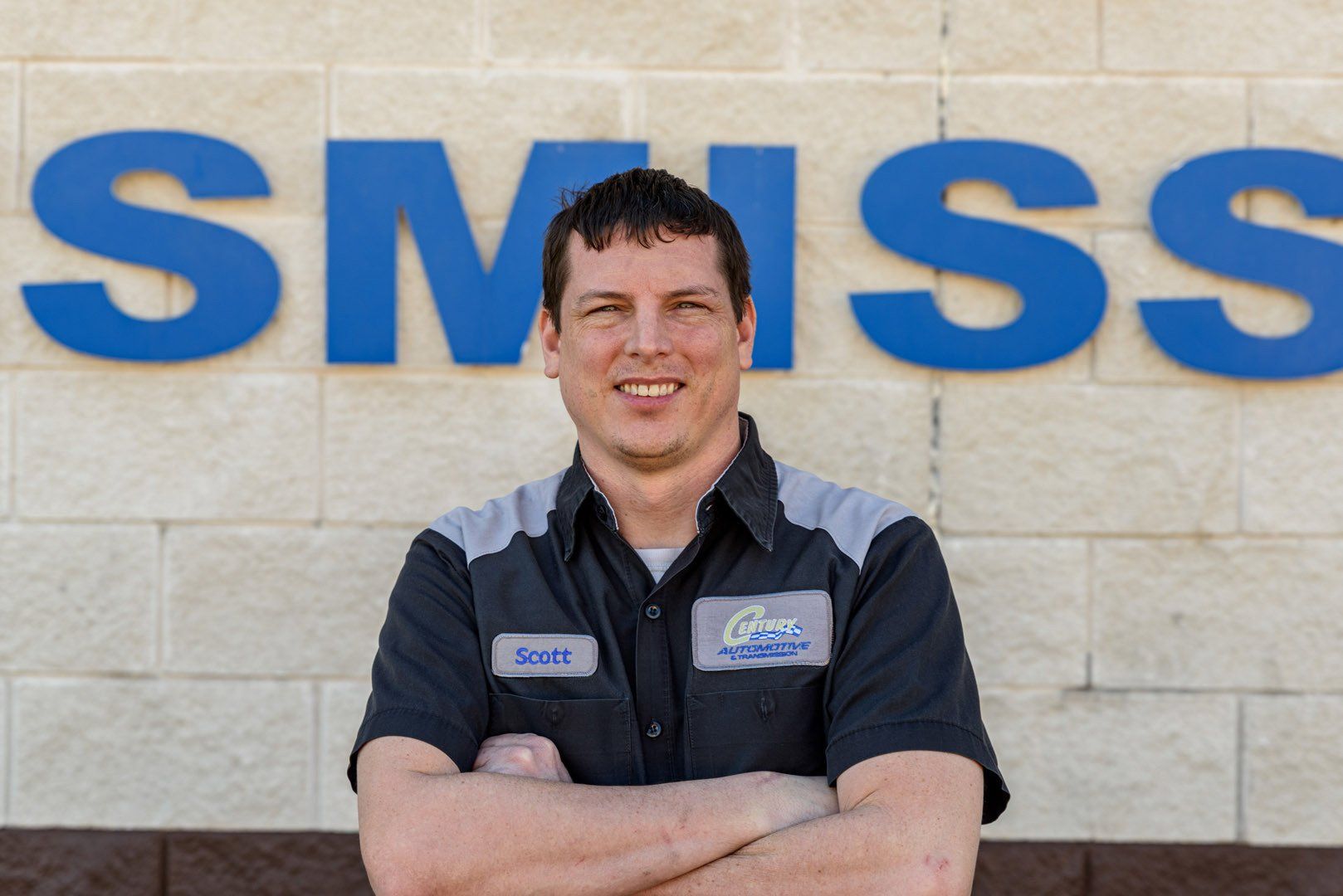 Man in work shirt with arms crossed, in front of