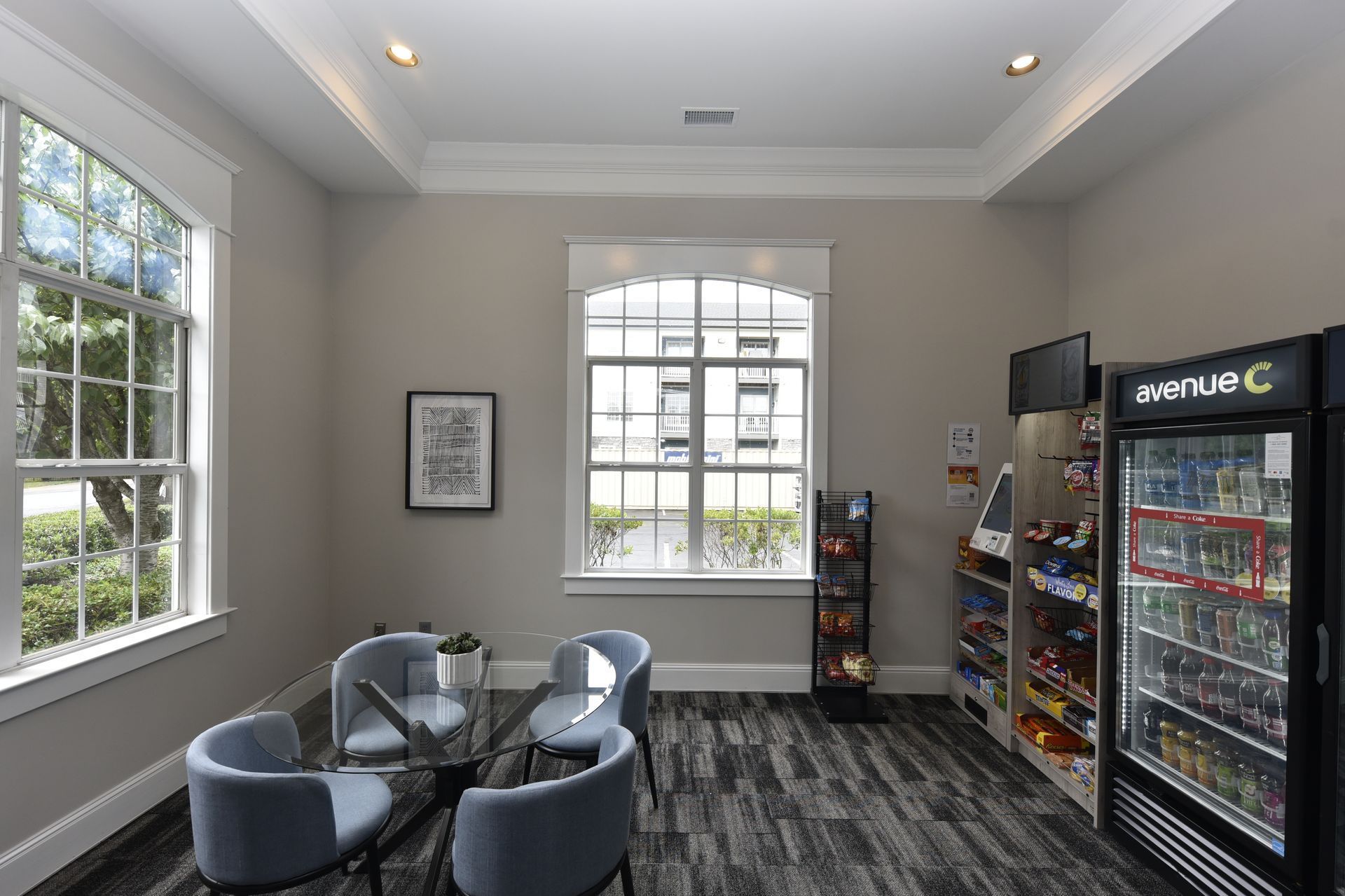 A waiting area with chairs and a table near a window. A vending machine and shelves stocked with snacks are visible.