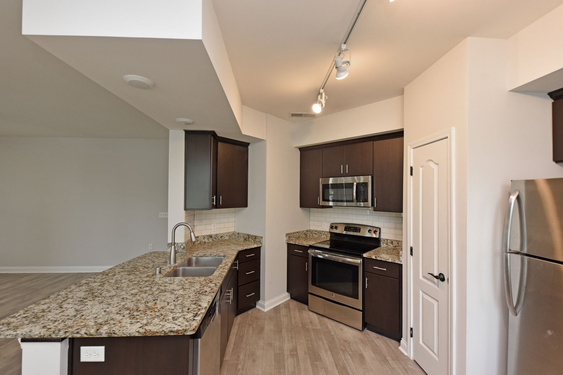 Modern kitchen with dark brown cabinets, stainless steel appliances, and granite countertops.