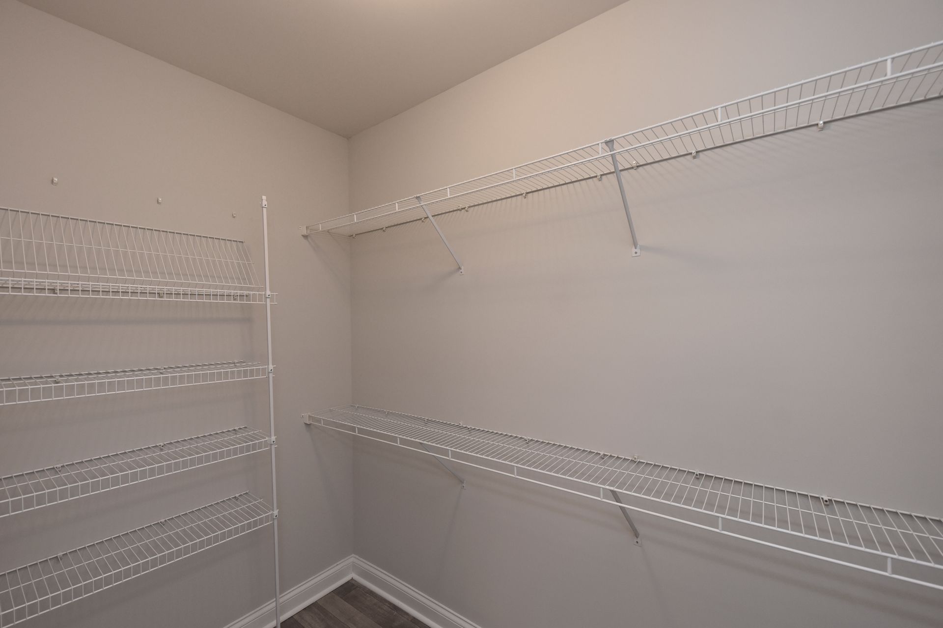 Empty pantry with white wire shelves against light gray walls.