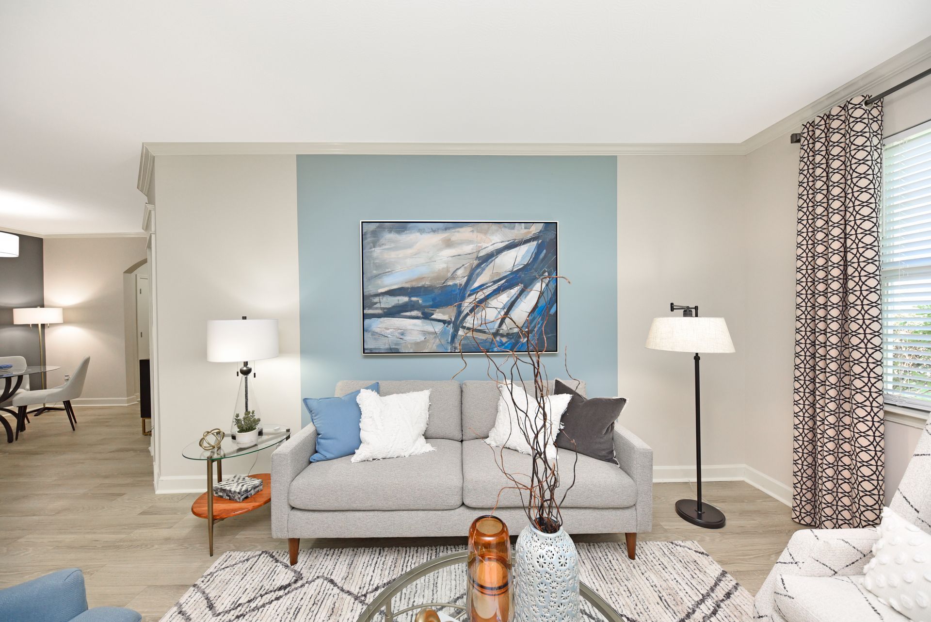 Living room with a gray sofa, blue accent wall, and abstract art.