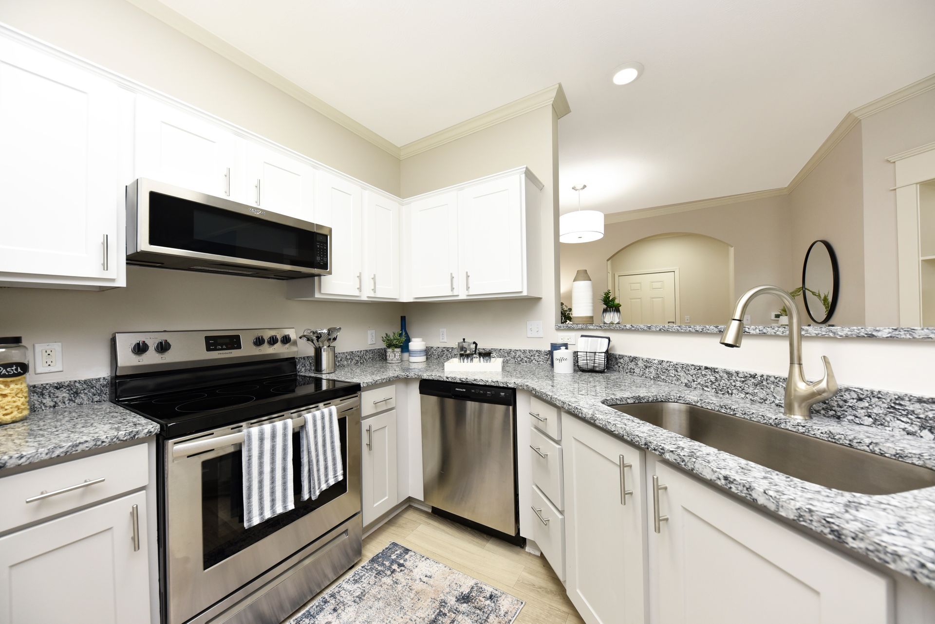 Modern kitchen with white cabinets, stainless steel appliances, and gray countertops.