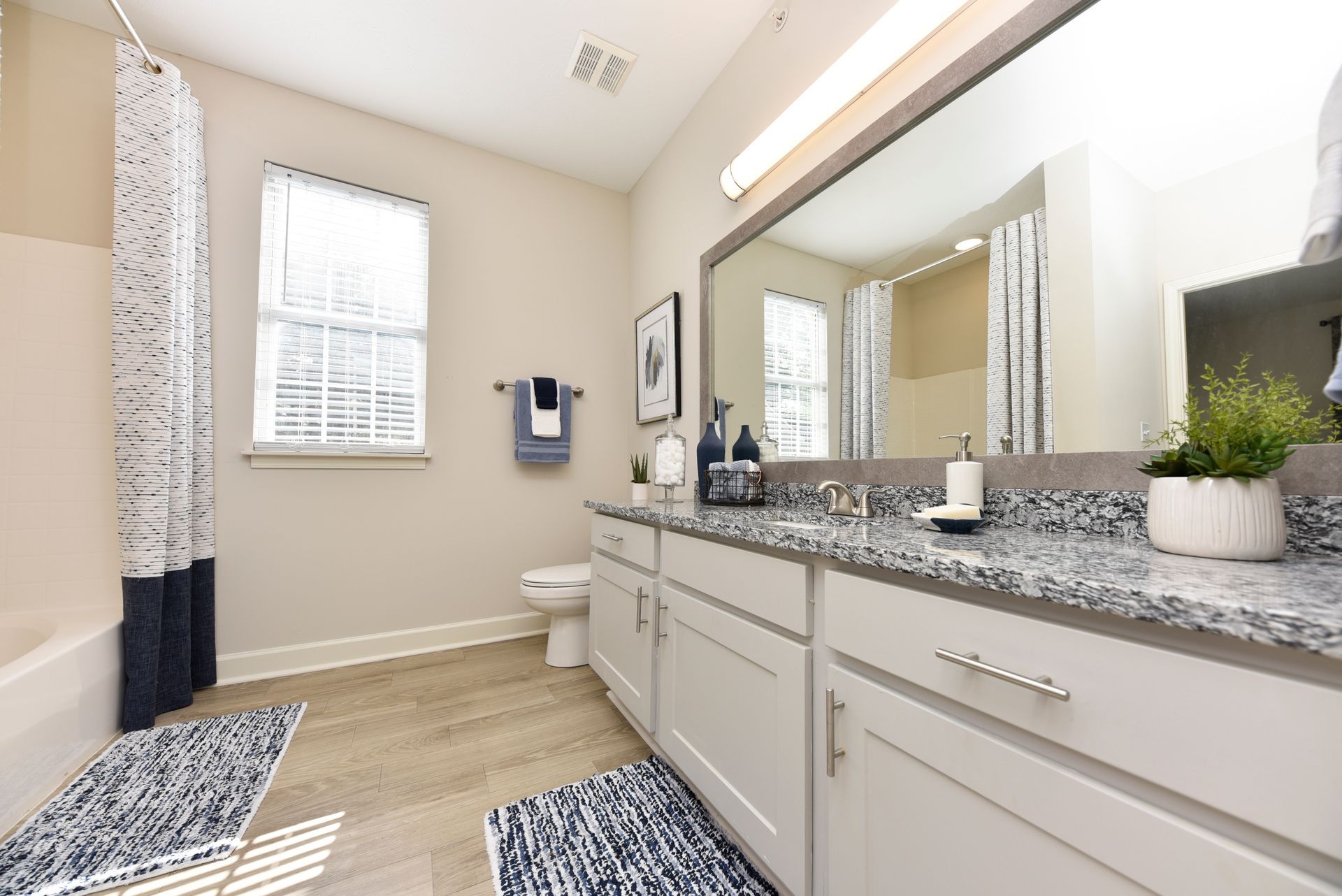 Bathroom with white cabinets, granite countertop, blue accents, and large mirror.