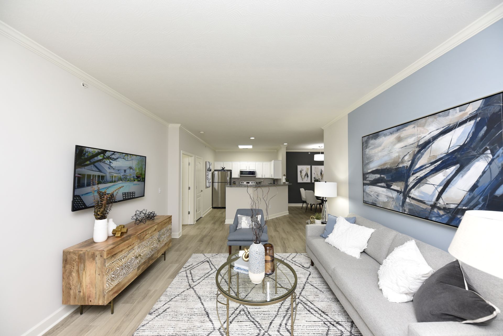 Living room with wooden console, TV, gray sofa, and blue accent wall.