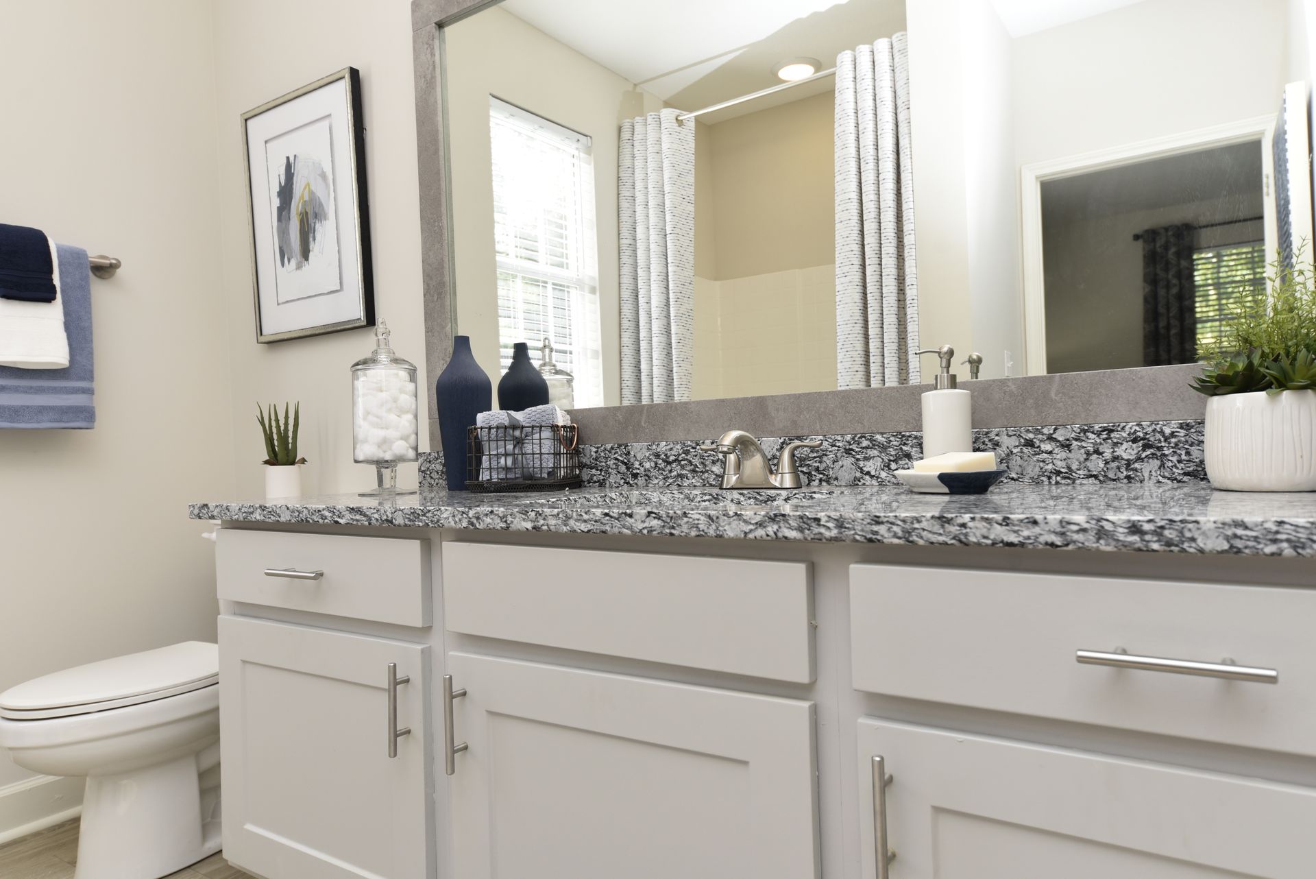 White bathroom with granite countertop, white cabinets, and silver fixtures.