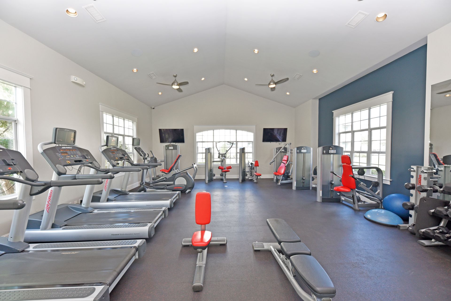 Gym interior with treadmills, weight machines, and free weights.