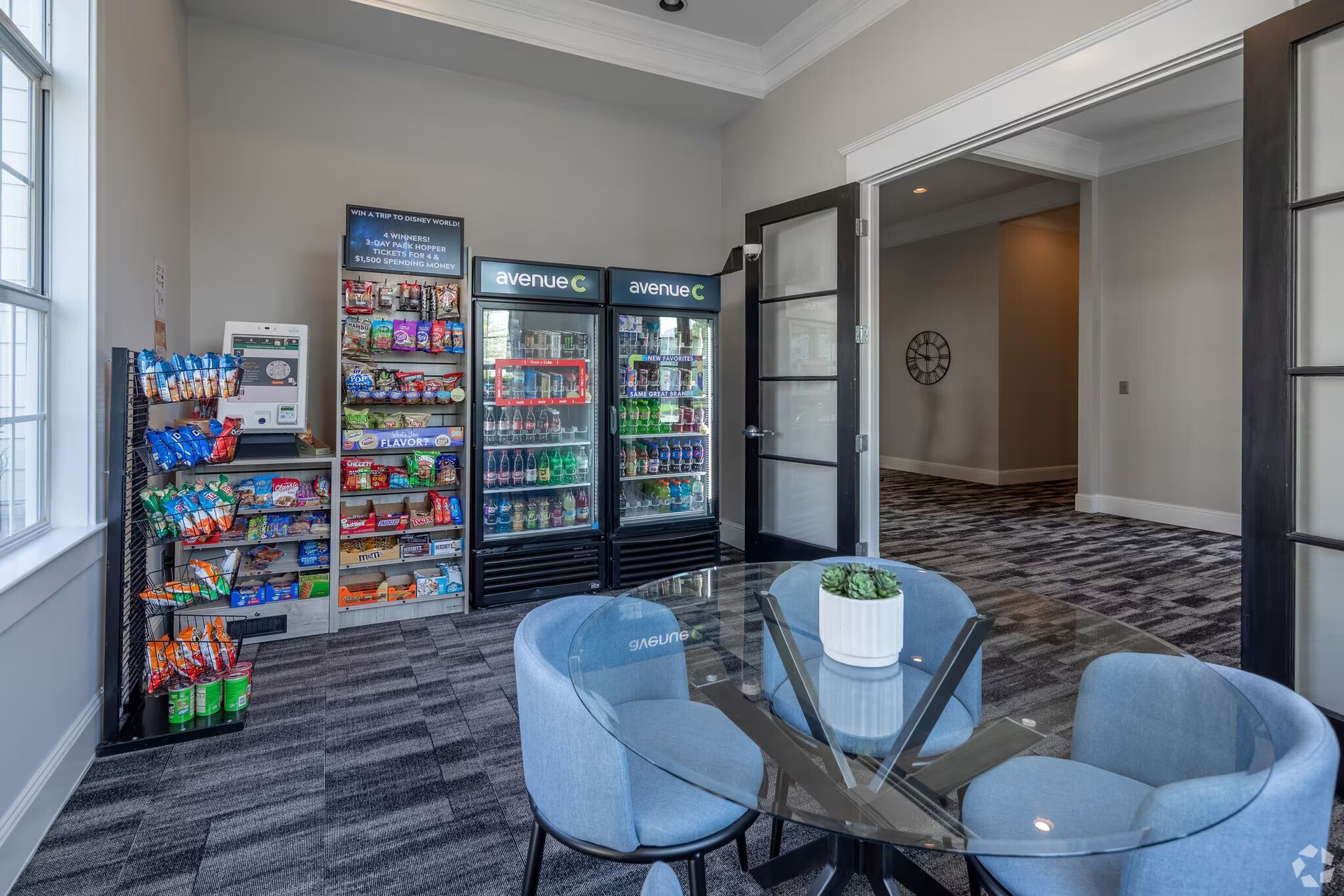 Vending machines and a table with blue chairs in a room.