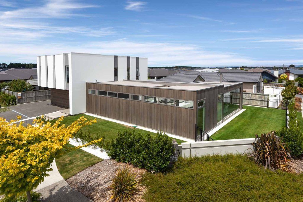 A large house with a lot of windows is sitting on top of a lush green hillside.