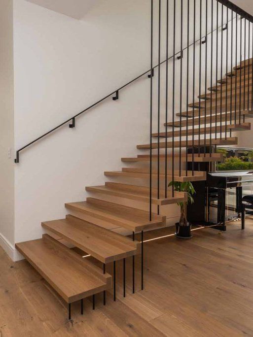 a modern wooden staircase with a metal railing in a house .