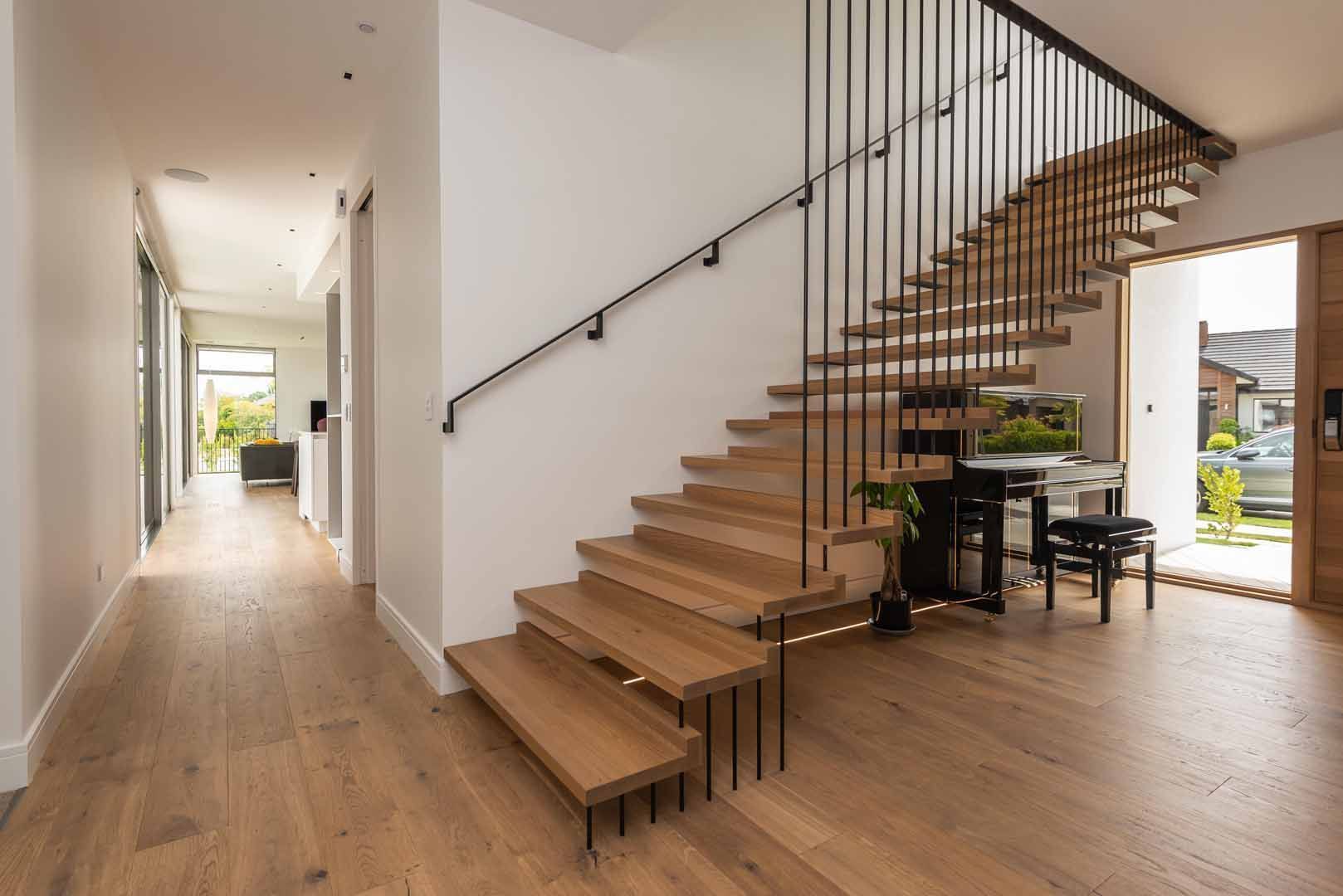 A wooden staircase with a black railing in a hallway in a house.