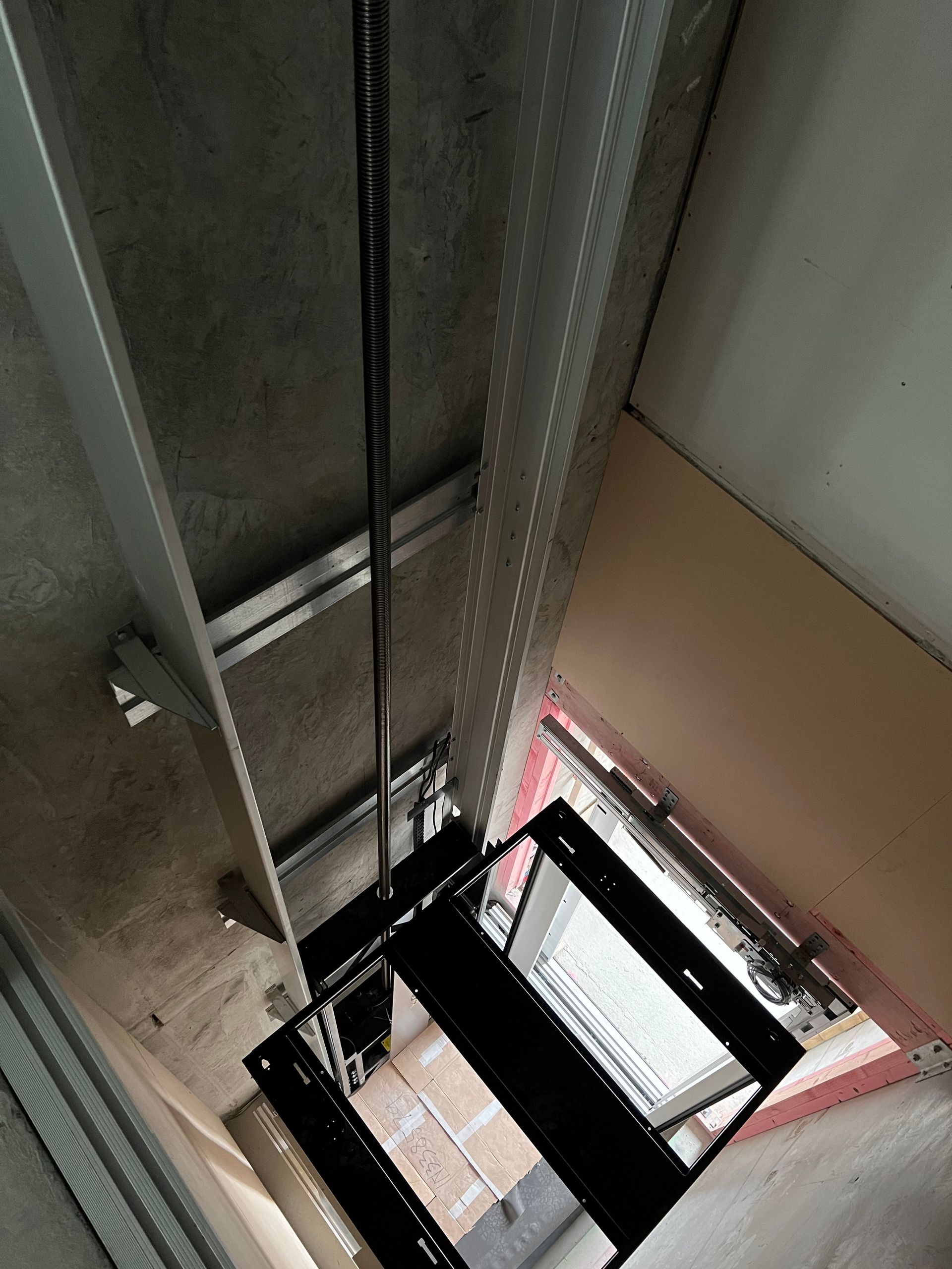 Looking up at a staircase in a building with a rope hanging from the ceiling.
