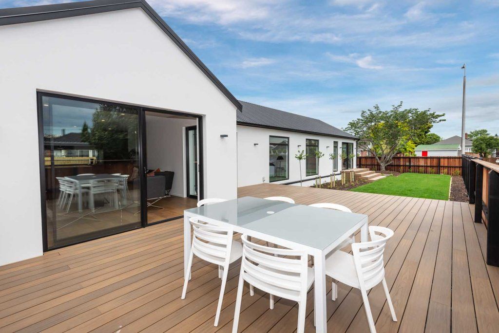 There is a table and chairs on the deck of a house.