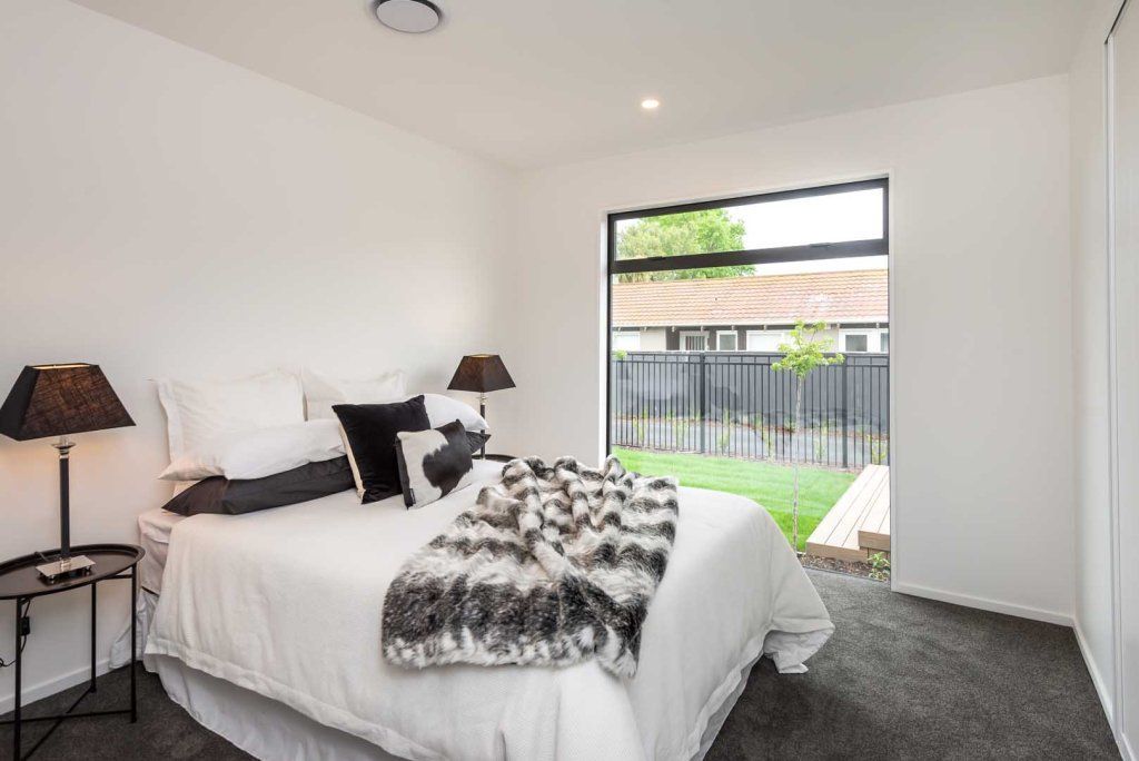 A bedroom with a bed , two lamps and a window.