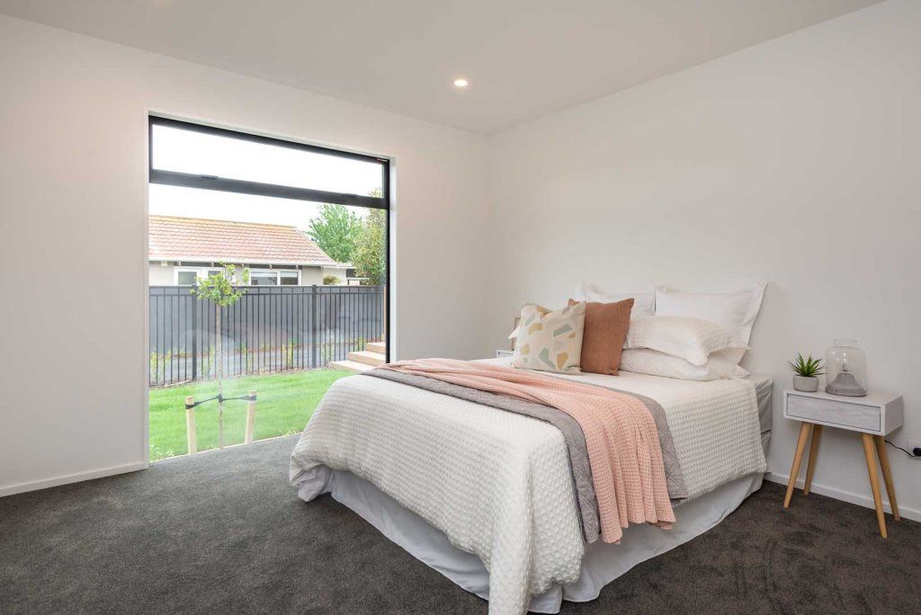 A bedroom with a bed and a window with a view of the backyard.