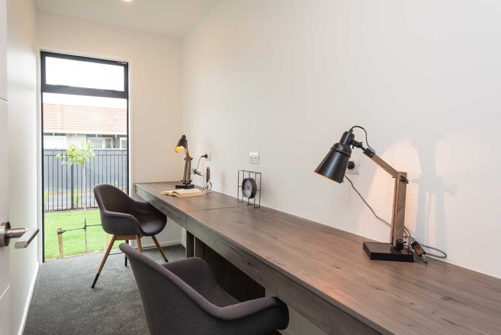 A room with a desk , chairs , lamps and a window.