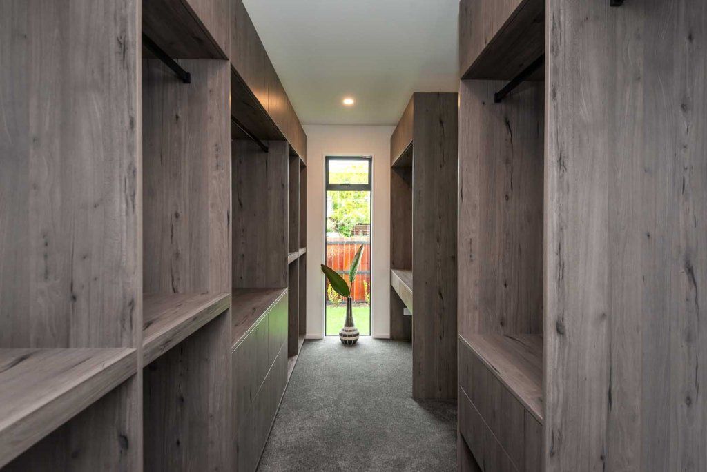 A walk in closet with lots of shelves and drawers in a house.