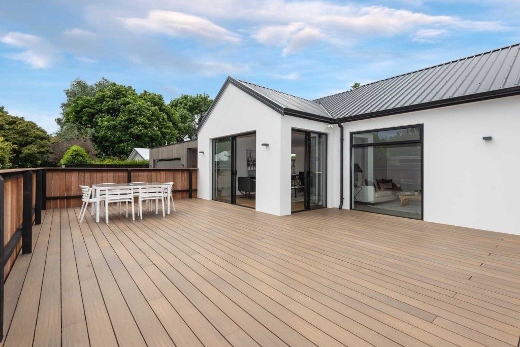 A large white house with a wooden deck and a table and chairs on it.