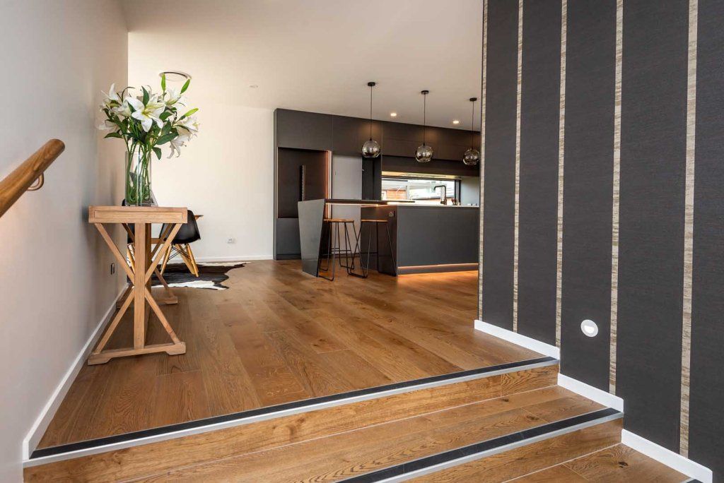 A wooden staircase leading up to a kitchen in a house.