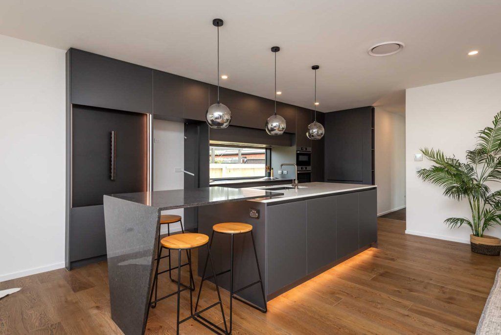 A kitchen with a large island and stools in it.