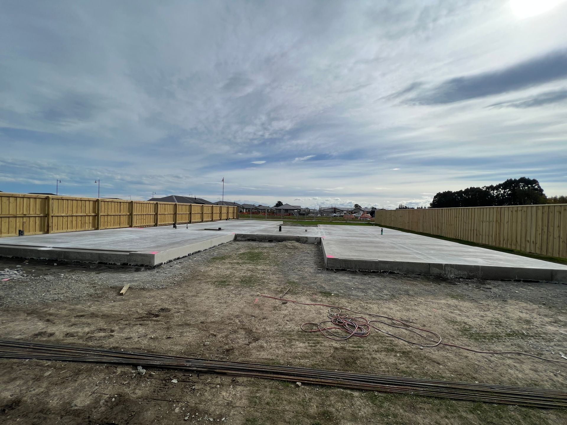 A large concrete slab is sitting in the middle of a dirt field next to a wooden fence.