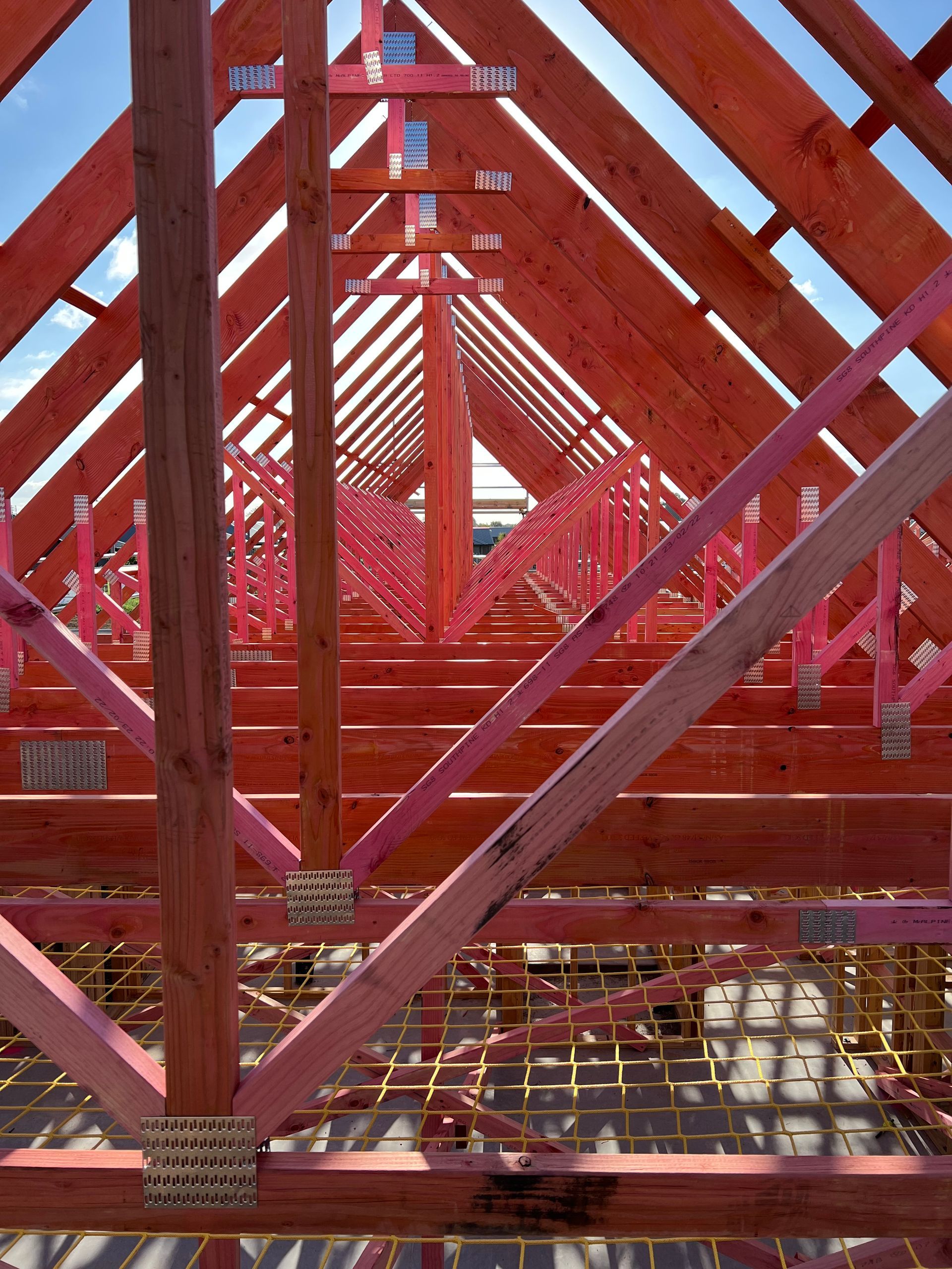 The roof of a building is being built with pink beams