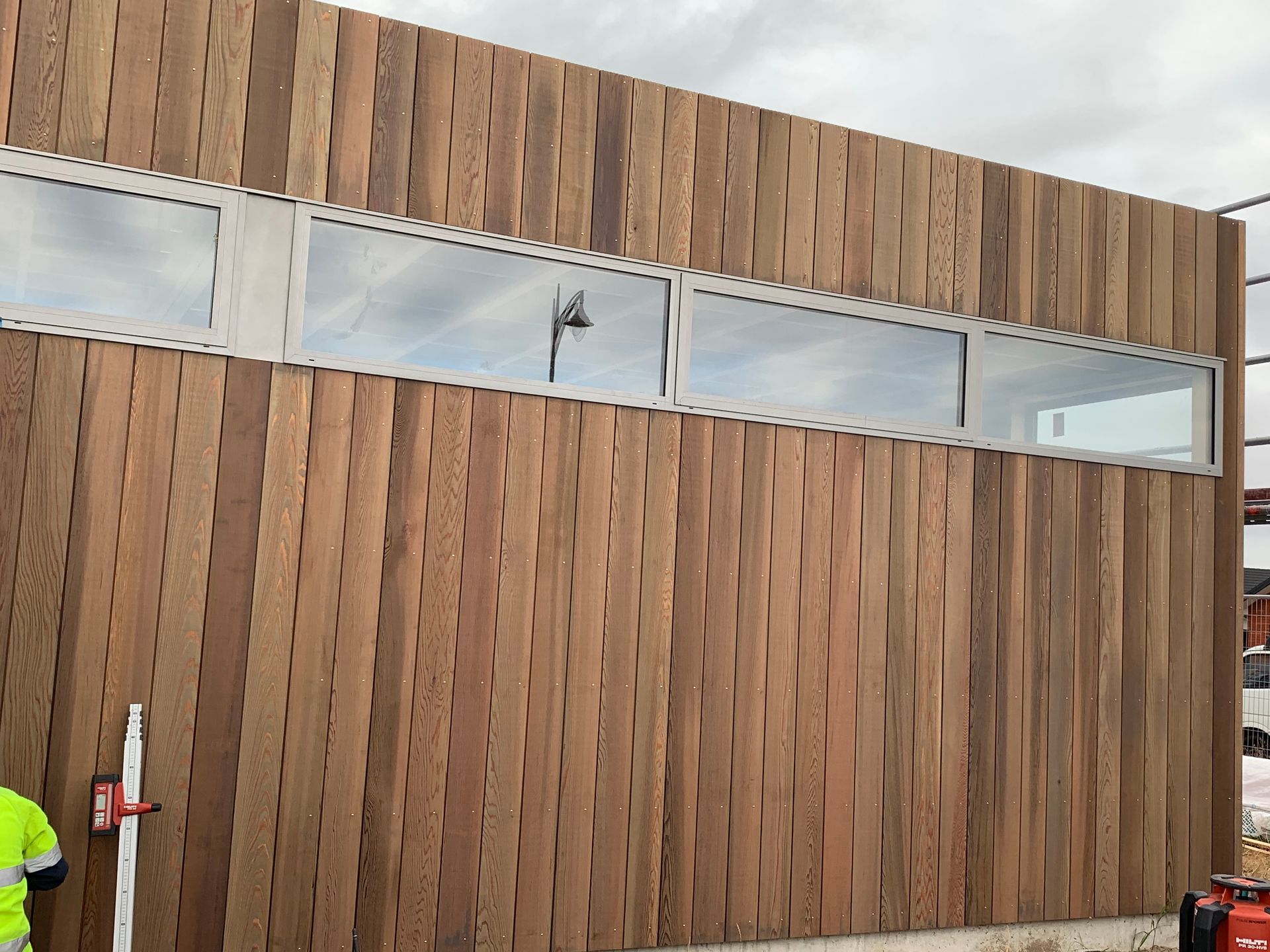 A man is standing in front of a large wooden building with a lot of windows.