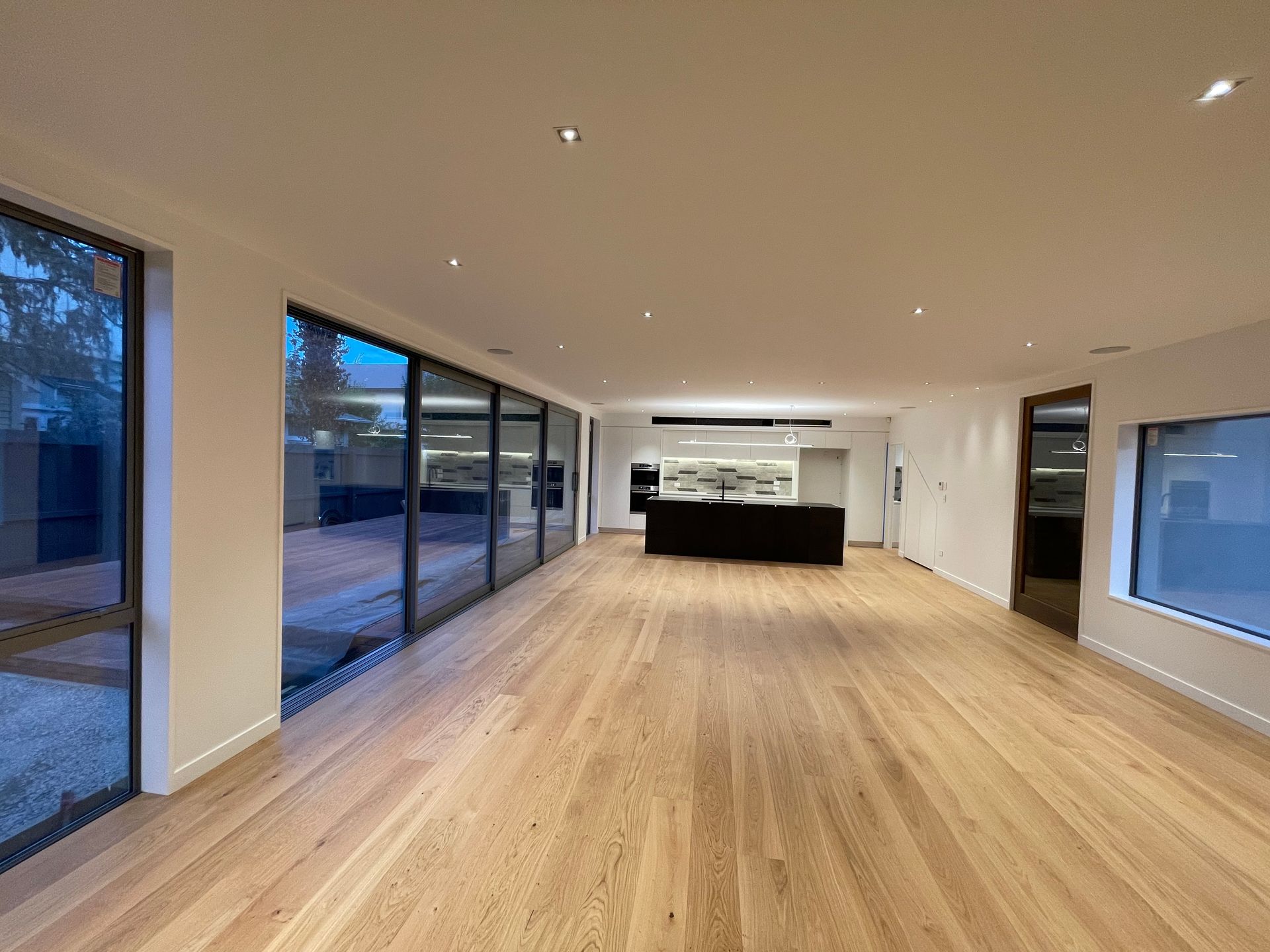 A large empty room with hardwood floors and lots of windows.