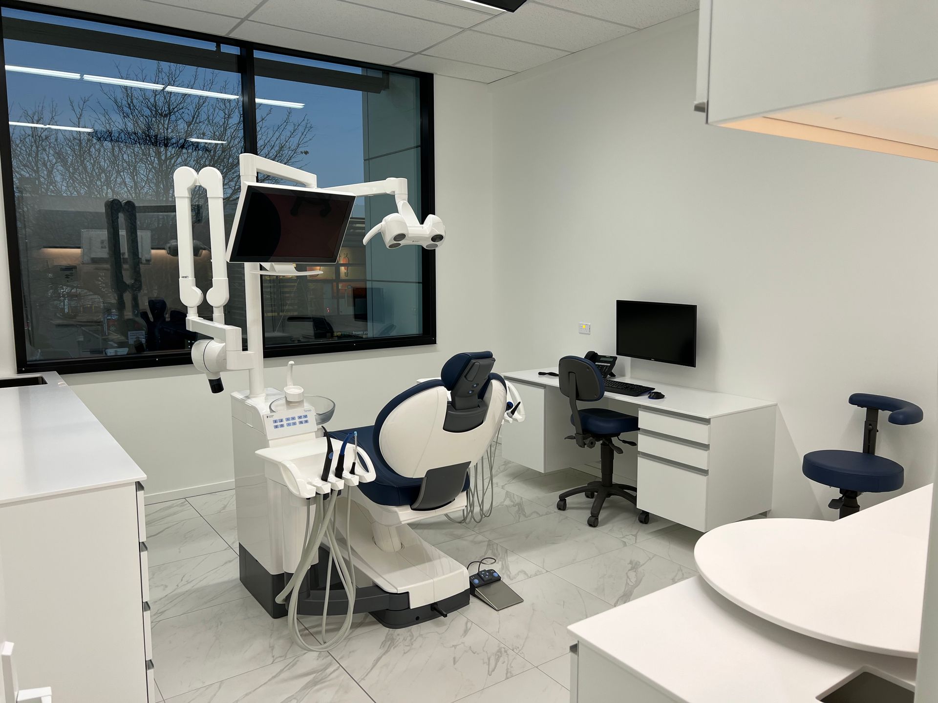 A dental office with a dental chair and a computer.