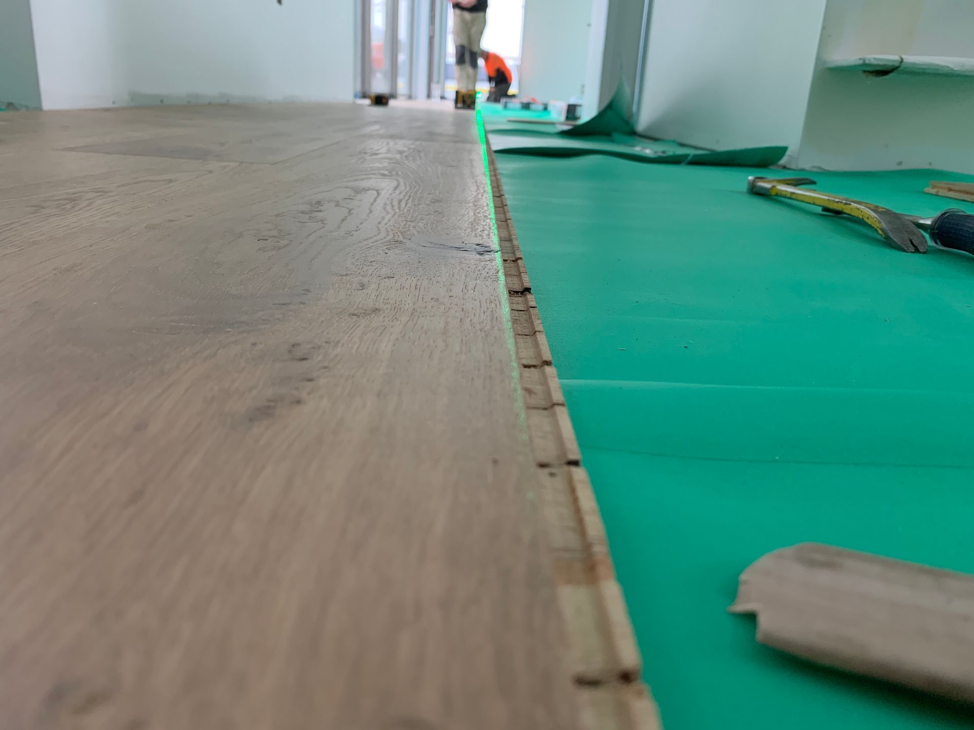 A wooden floor is being installed on a green mat.