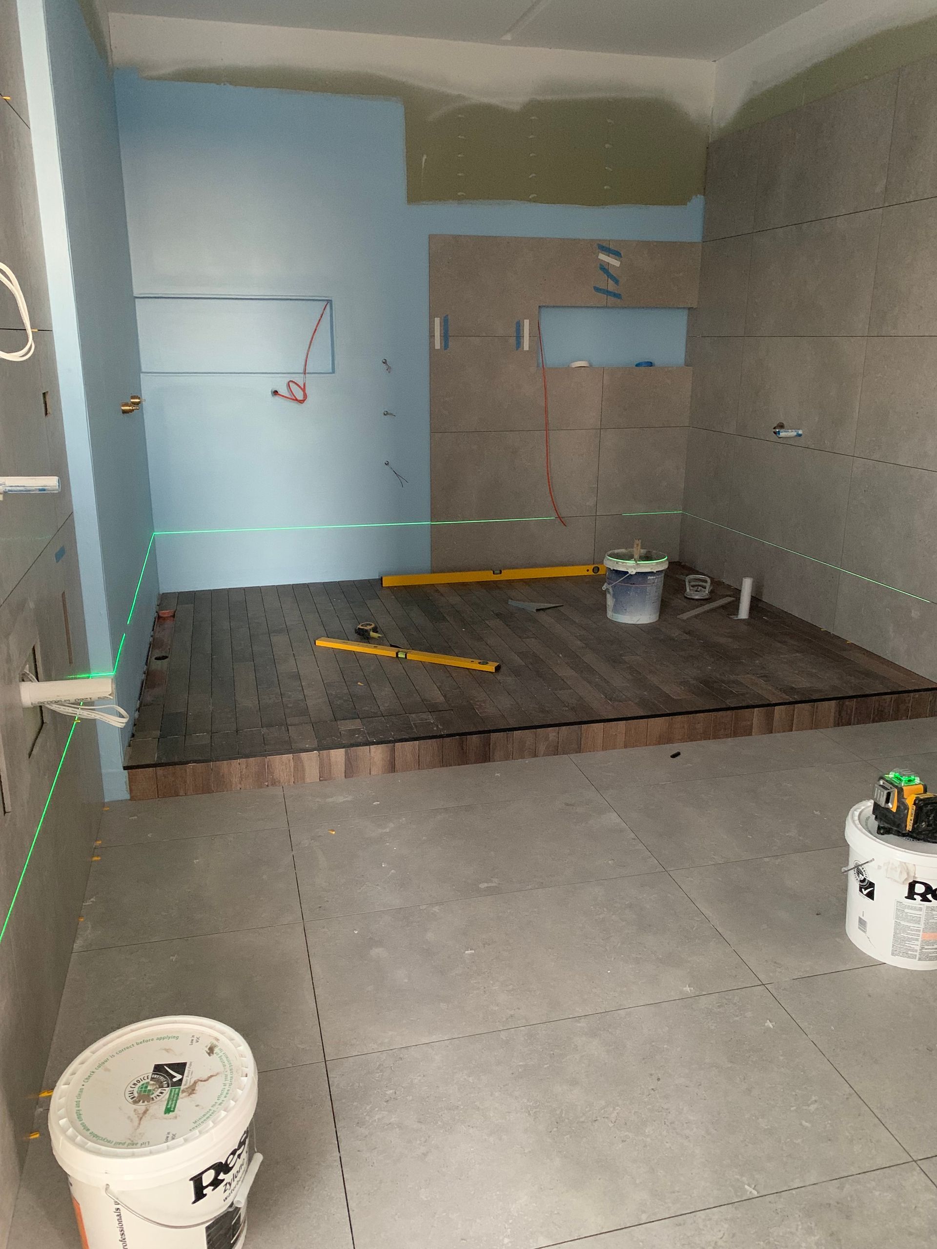 A bathroom under construction with a green laser on the wall.