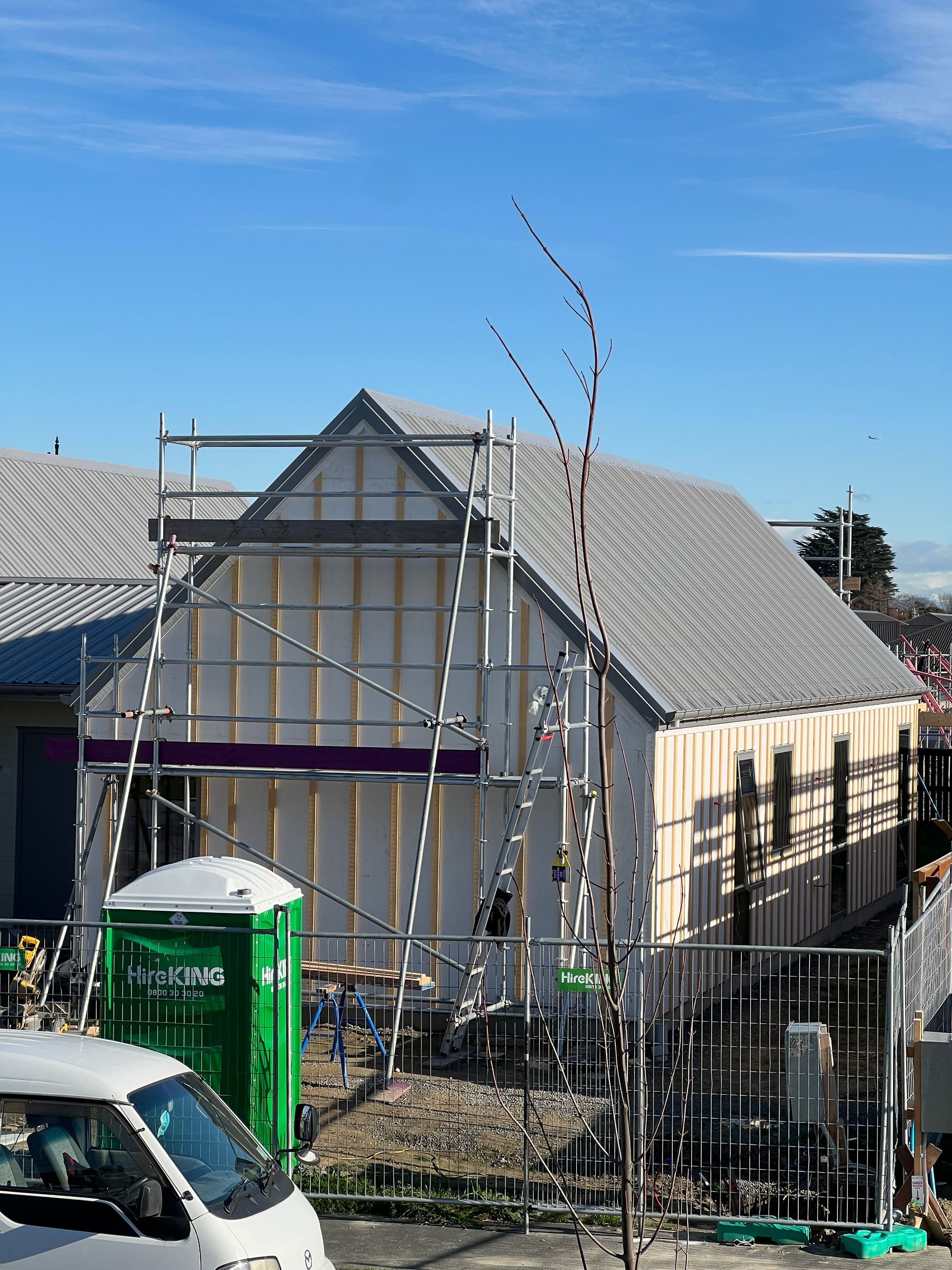 A white van is parked in front of a building under construction