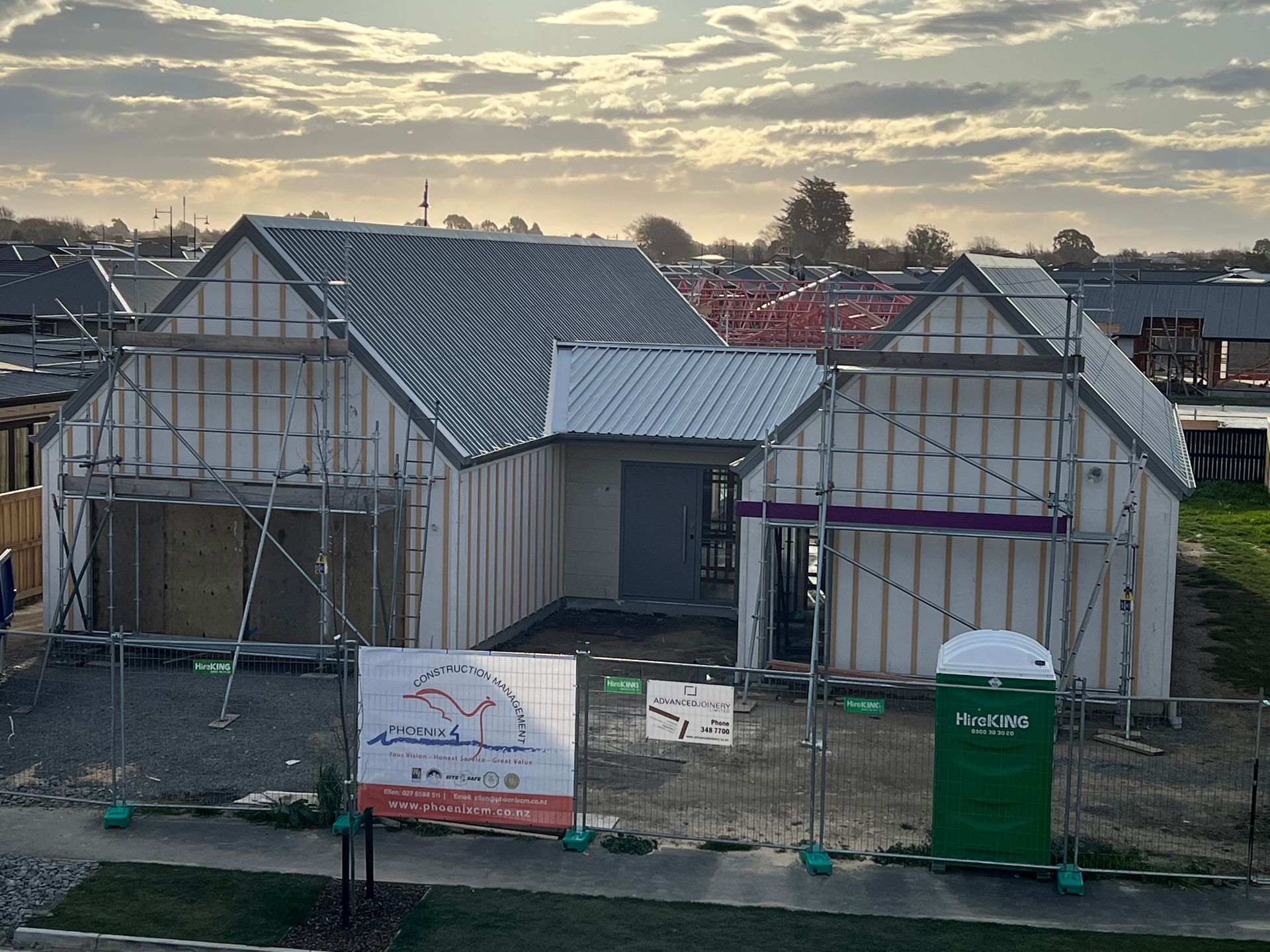 A house is being built in a residential area with scaffolding around it.